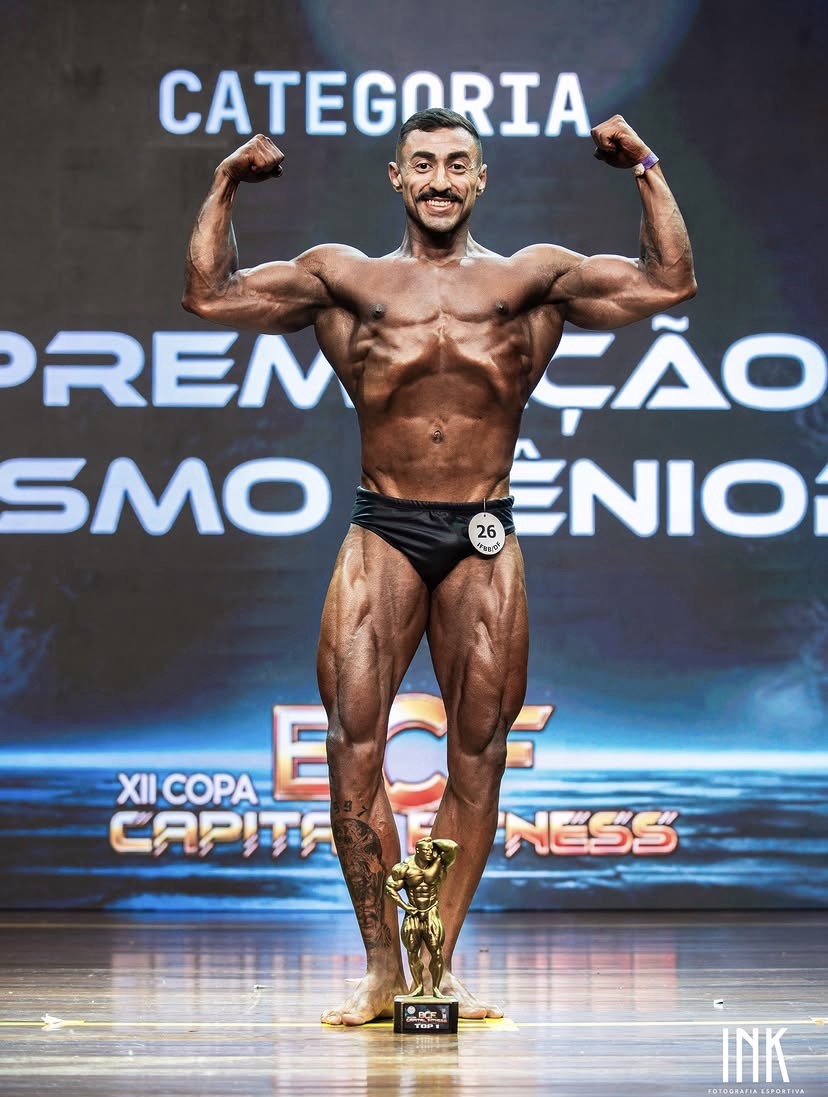 Lucas Barnabé no palco de fisiculturismo com seu troféu